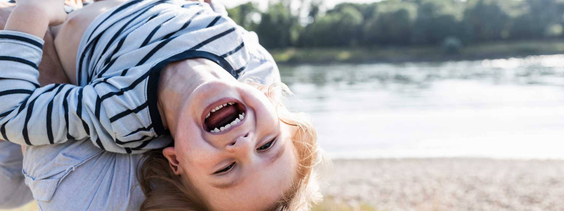 girl hanging upside down from her father's shoulders